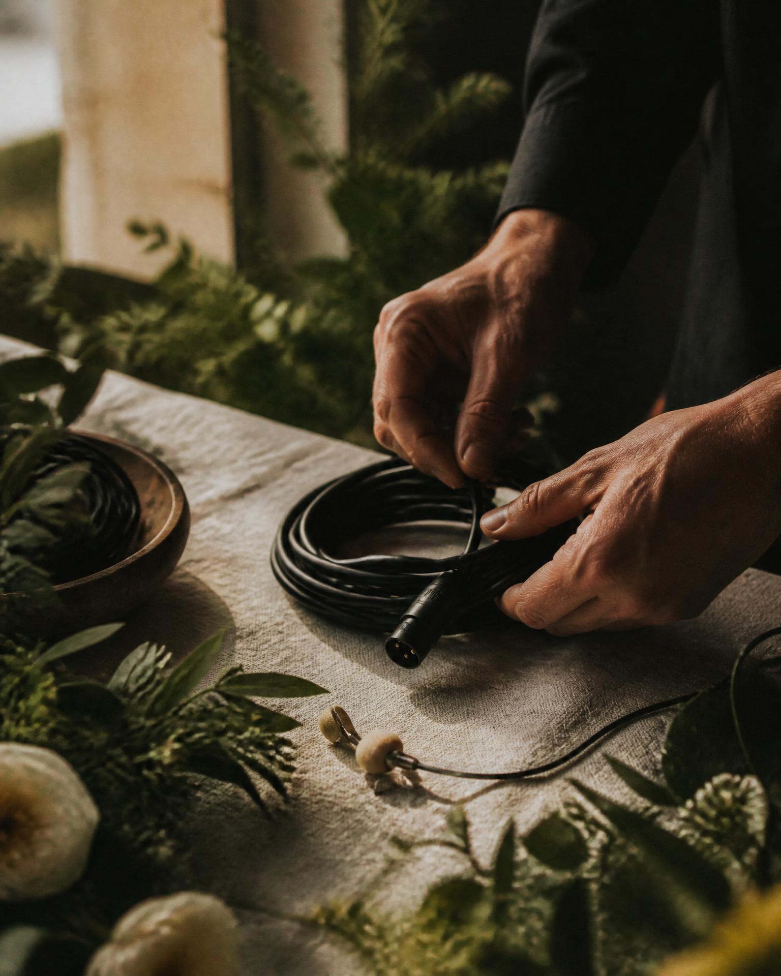 Hands coiling an XLR audio cable on a linen surface